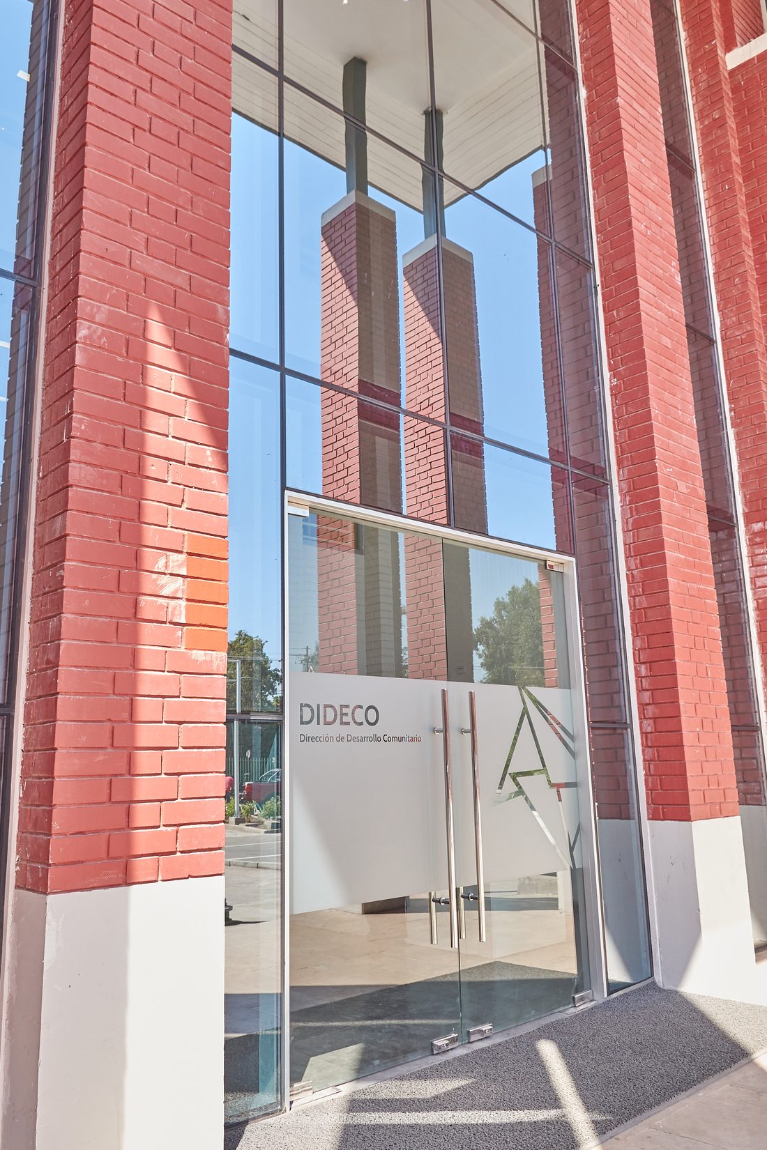 Acceso principal del edificio Dideco con muro cortina y puertas de vidrio