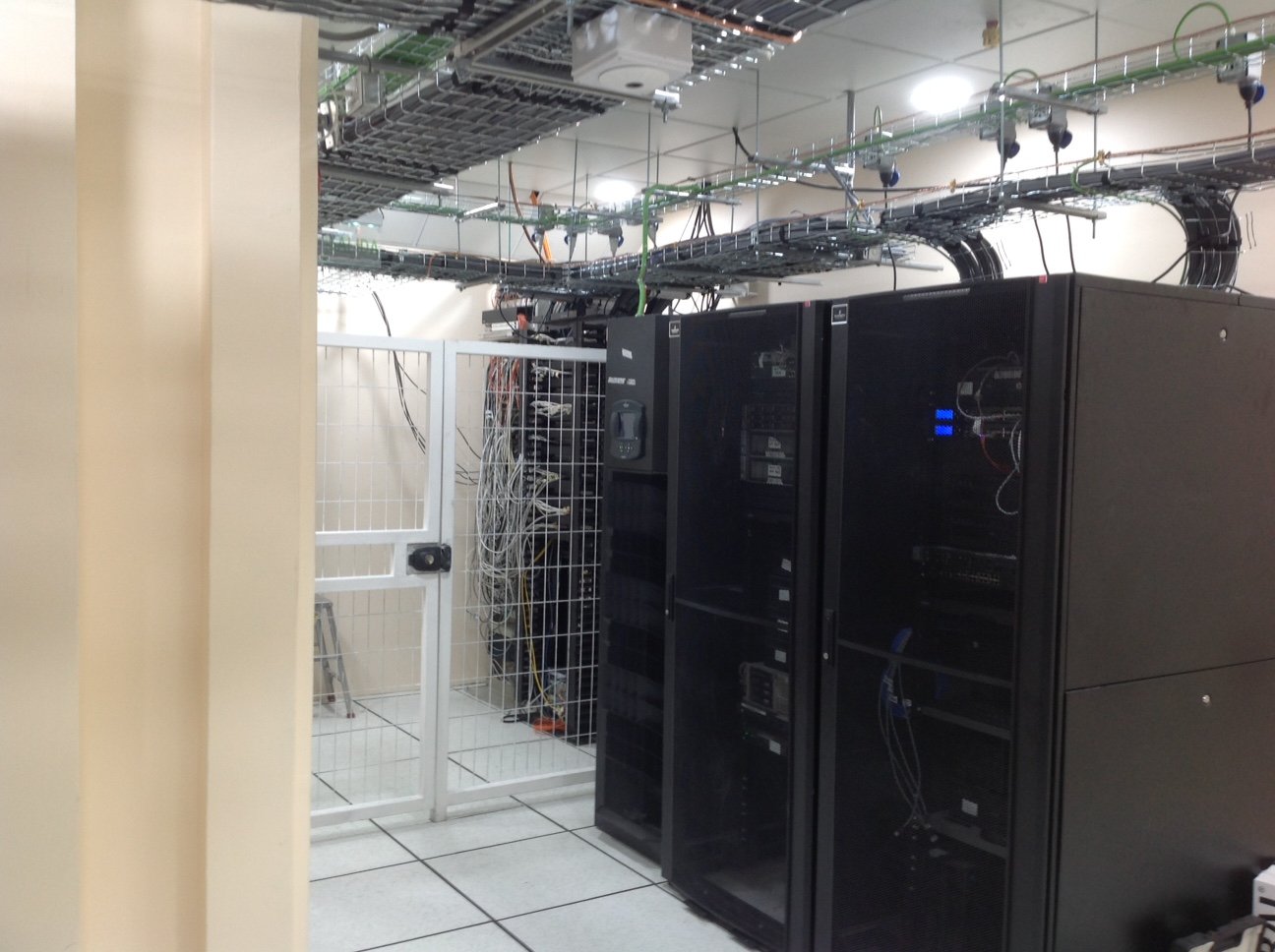 Racks de servidores y bastidor de comunicaciones con bandejas portaconductores y cableado Cat 6A sobre piso técnico en data center FONASA